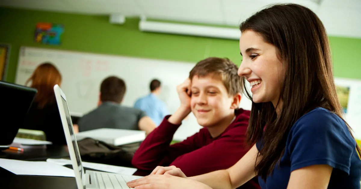 Een student helpt leerlingen in de klas